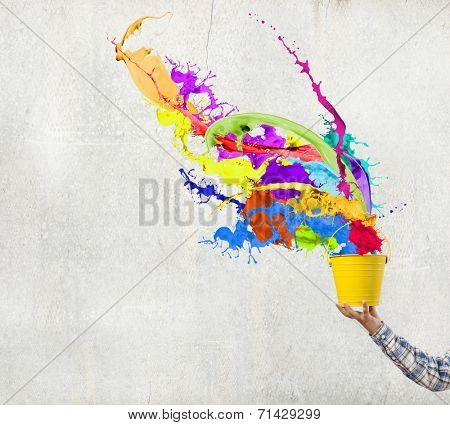 Close up of hand splashing colorful paint from bucket