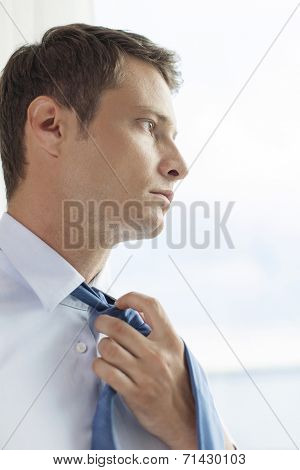 Close-up of pensive businessman loosening necktie in hotel