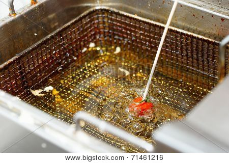 Tomato being fried in oil at professional kitchen