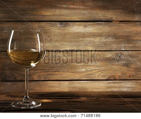Goblet of white wine on wooden table on wooden wall background