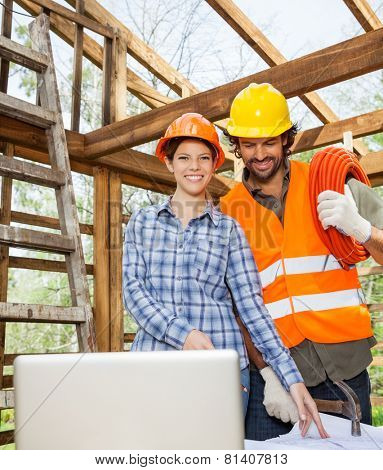 Portrait of smiling female architect working with construction worker at site