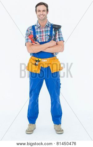 Full length portrait of confident plumber holding monkey wrench and plunger over white background
