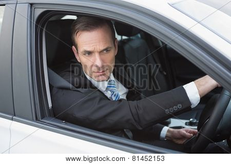 Unsmiling businessman in the drivers seat in his car