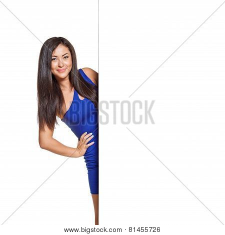 Young pretty woman peeking out from behind the wall