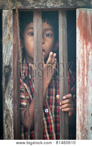 Unidentified Indian boy looks through window at home