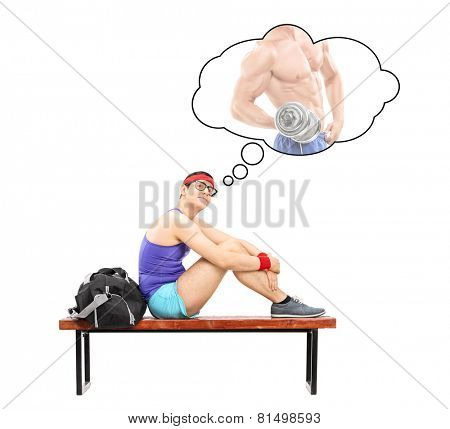 Nerdy guy imagining himself as a bodybuilder seated on a bench isolated on white background