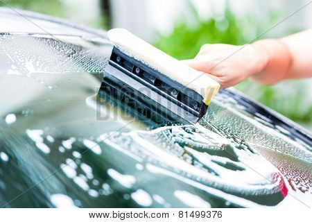 man cleaning windscreen while car wash