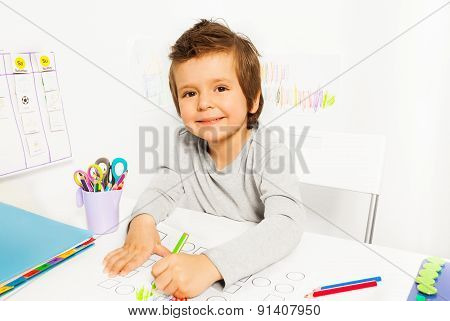 Positive small boy draws with pencil during ABA