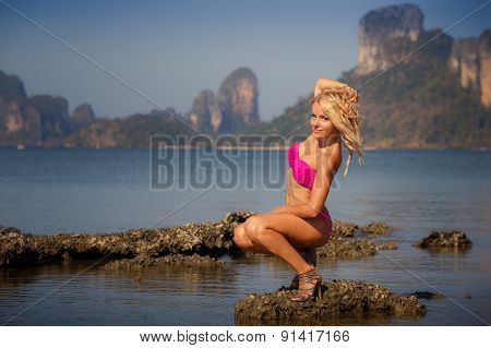 Blonde Girl In Swimsuit  Smoothes Hair On Stone