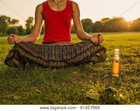 Woman Meditating In Park At Sunset