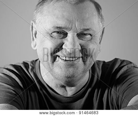 Black and white portrait of cheerful aged man in t-shirt smiling with dimples