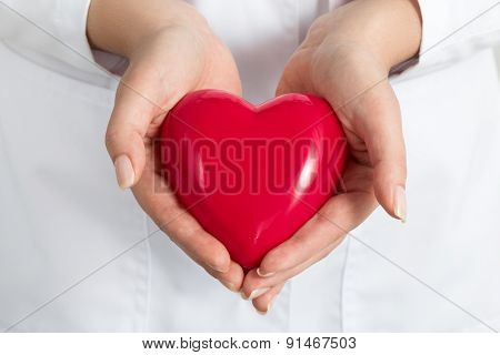 Female Doctors's Hands Holding And Covering Red Heart