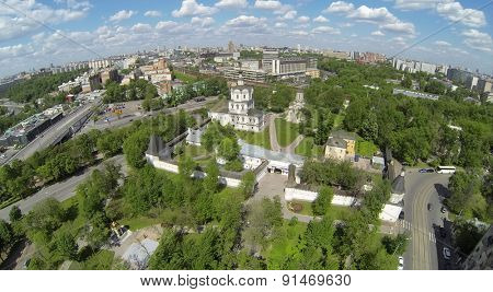 RUSSIA, MOSCOW - MAY 14, 2014: Spaso-Andronikov monastery against city with traffic on river embankment and railroad at sunny day. Aerial view.