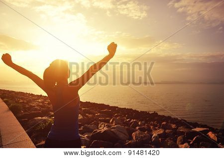 woman open arms under the sunrise at sea