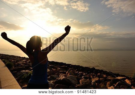 woman open arms under the sunrise at sea