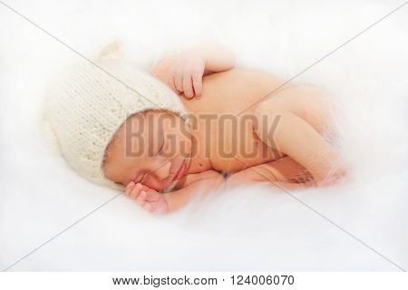 Sleeping happy newborn baby in the white fur. Birth and new life concept.