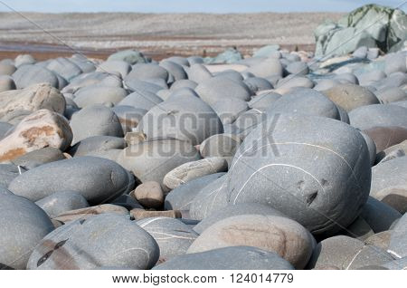 Pebbles at the beach in the foreground of a coastal scene