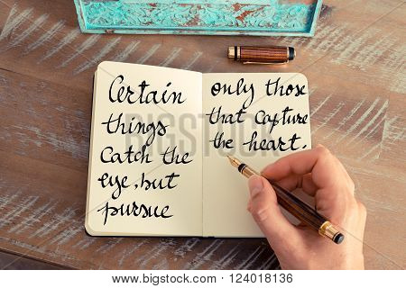 Retro effect and toned image of a woman hand writing on a notebook. Handwritten quote Certain things catch your eye but pursue only those that capture the heart as inspirational concept image
