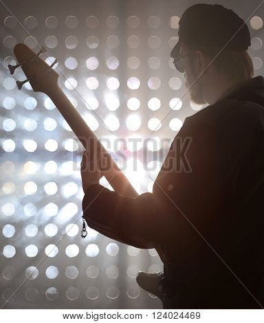 Bassist playing bass guitar in smoke. backlight