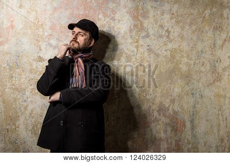 image of a caucasian man with grungy blond hair dressed warmly in a stylish black trench coat and a funky hat and scarf for the cold winter