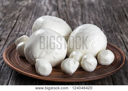 mozzarella balls on a clay dish on an old rustic table close-up
