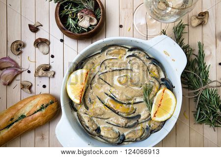 Mussels backed in cream sauce with rosemary on wood background.