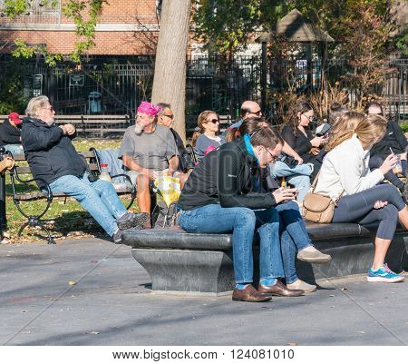 Manhattan New York - December 06 2015: People sitting on the benches during lazy Sunday afternoon in Washington Square Park.