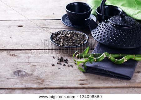 Green tea in bowl and traditional asian tea set on aged wooden background. Selective focus is on tea. Place for text.
