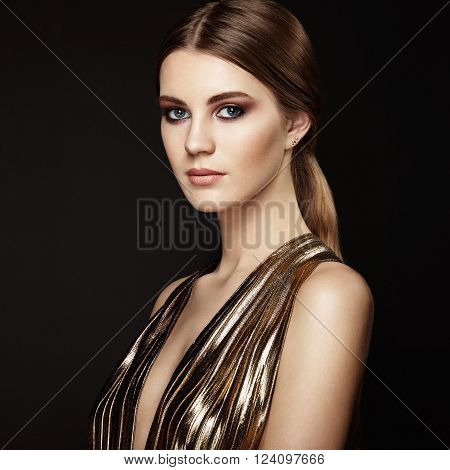 Fashion portrain of young beautiful woman in gold dress. Brunette glamour lady with perfect make up and hairstyle