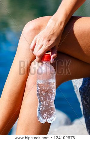 Female hand holding a bottle of mineral water outdoors