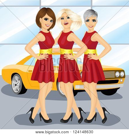 Three beautiful hostess women in red deresses by the yellow car on motor show