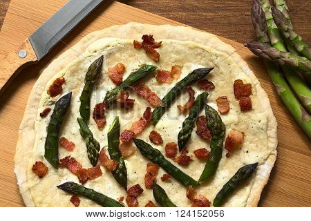 Green asparagus and bacon tarte flambee or Flammkuchen, a typical Alsatian and South German dish, photographed overhead with natural light