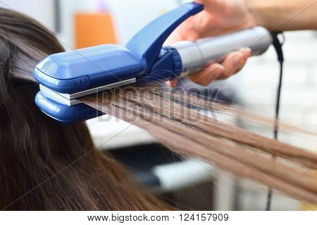 Straightener. Hairdresser hairstyle beautiful model using straightener.