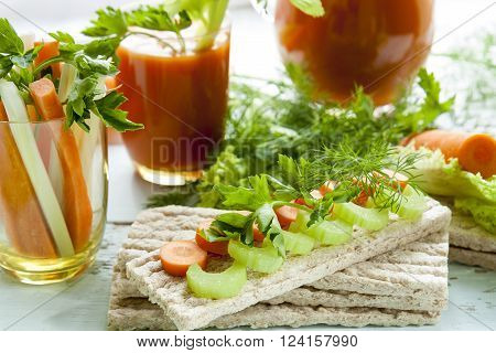 Plain rye cakes galette rye with fresh carrots celery and parsley around fresh carrot juice fresh carrot and celery on light background