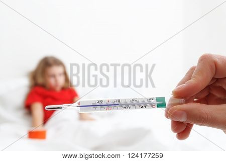 pediatric doctor hand holding a thermometer indicating fever with blury child in background