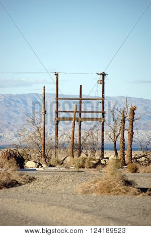 A radio mast and telephone pole standing in the desert at the Salton Sea in the ghost town of Salton City.