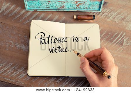 Retro effect and toned image of a woman hand writing on a notebook. Handwritten quote Patience is a Virtue as inspirational concept image