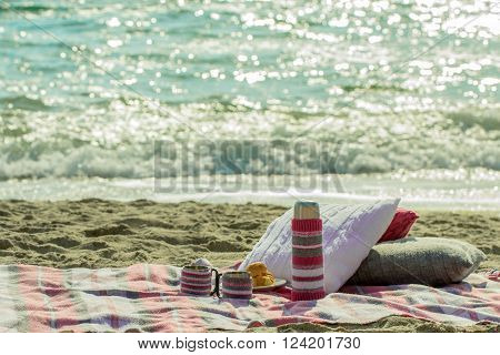 Breakfast on the beach. Coffee and croissants on the sea. Pillows slipcover a thermos bottle and Cup - hand-knitting.