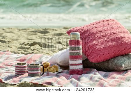 Breakfast on the beach. Coffee and croissants on the sea. Pillows slipcover a thermos bottle and Cup - hand-knitting.