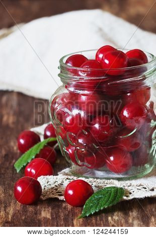 Fresh ripe cherries in a glass jar on the vintage wooden table. Preservation of products concept. Bio healthy food. Organic fruits. Selective focus