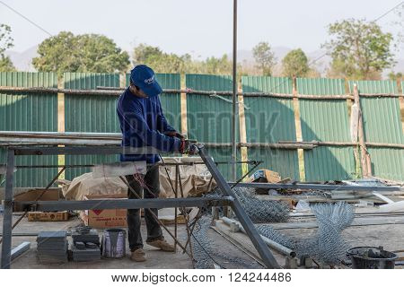 Petchaburi, Thailand - February 20, 2016: One man worker cut iron frame for making fence at prepared area for construction on February 20, 2016 in Petchaburi, Thailand