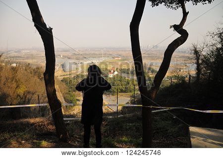 A chinese woman taking pictures from an elevated view of Chenshan Botanical Gardens in Shanghai China in the early spring.
