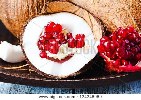 Fresh Coconut And Red Garnet In A Wooden Bowl,blue Background