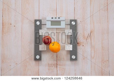 Apple and an orange are on the electronic scales