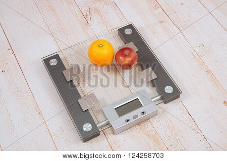 Apple and an orange are on the electronic scales