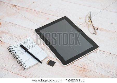 Digital tablet notepad pen glasses lying on a wooden table