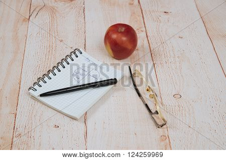 ballpoint pen glasses and an open notebook lying on the table