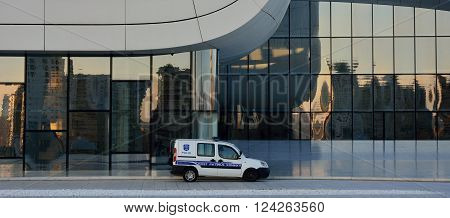 BAKU, AZERBAIJAN - MARCH 22 2014 
Police car in front of the Heydar Aliyev Centre. An Azerbaijani policeman sits in his car in front of an iconic modern building designed by Zaha Hadid, in the centre of Baku