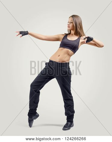 Girl dancer standing sideways and leaning back with lifted up left hand bent at the elbow. Right leg raised on tiptoes. Dance moves.