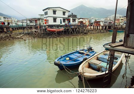HONG KONG, CHINA - FEB 11: Riverboats in dirty river of old fishermen village Tai O with rustic houses on February 11, 2016. Hong Kong dollar is the eighth most traded currency in the world